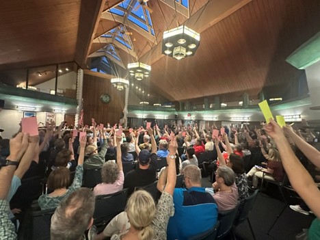 Maine Township residents raise their cards voting in support of the measure for the Township to purchase the property at 9850 Milwaukee Ave. in Glenview to move the Food Pantry